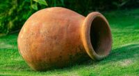 Large weathered terracotta urn lying on a grassy garden lawn